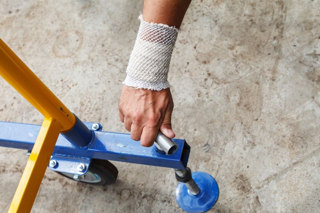 worker with a bandaged patient hand twisting the locking screw on a metal structure t20 ywZPw2
